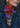 Woman wearing a retro print bandanna in bright cherry red and electric blue with a stack of silver Navajo pearls layered over it.