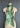 At Home With Ray Cactus Rose Silky Ribbon Scarf in Saguaro sage green displayed on a dress form tied in a long elegant necktie style, showing the full illustrated southwestern design from cowgirl to owl and cactus motifs.