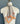 The "Frolic in Khaki" scarf from At Home With Ray takes center stage, adorned with small blue and orange motifs that exude a timeless charm. The beige checkered scarf, crafted from a luxurious silk/cotton blend, is elegantly tied at the neck for a sophisticated appearance. The "Wolf" label at the neck adds a finishing touch.
